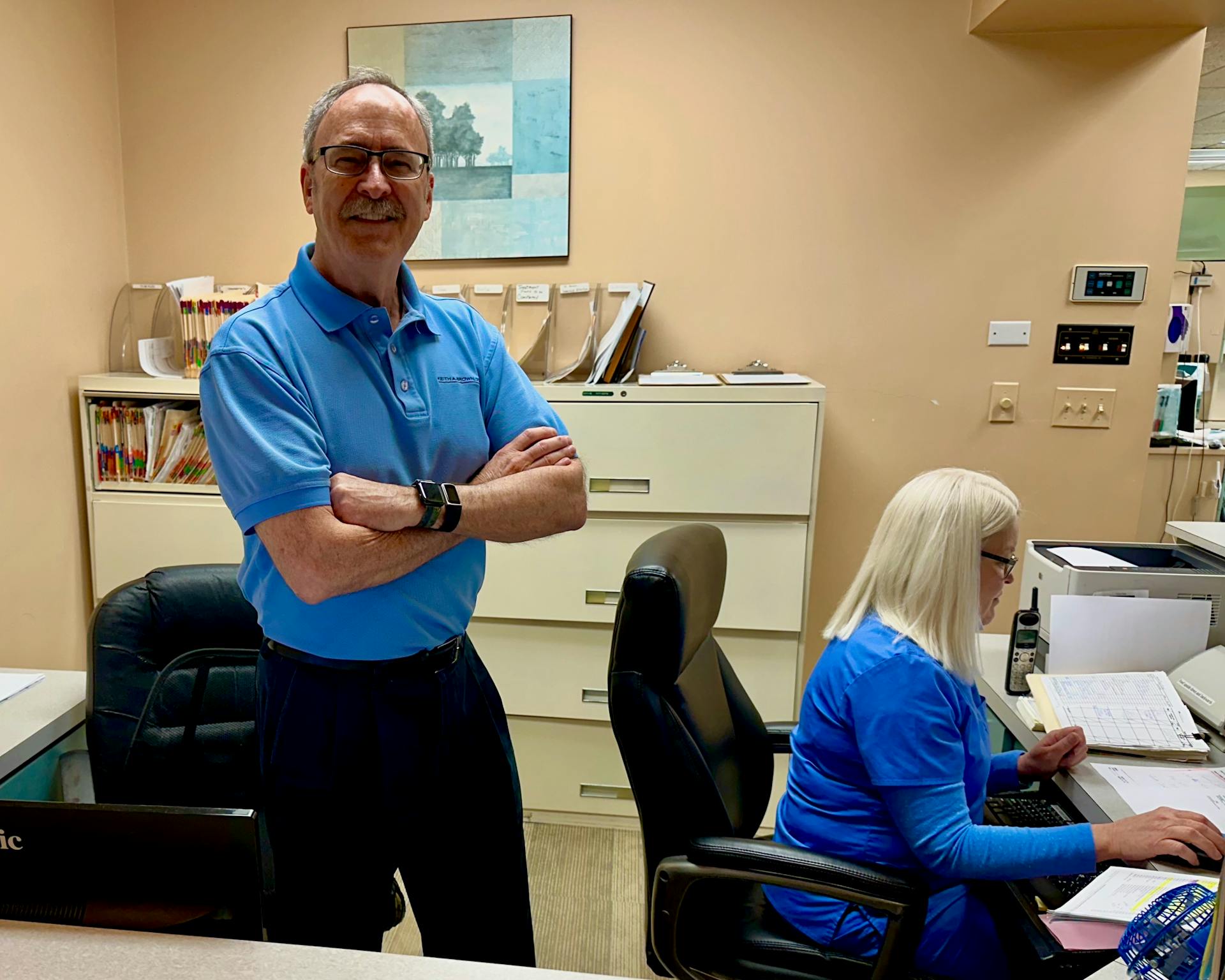 Dr. Keith A. Brown DDS, FAGD, at the dental office reception desk in Naperville, IL.